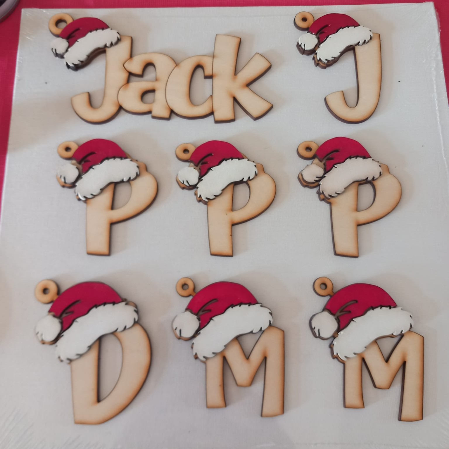 Laser-cut wooden initial decorations with red and white Santa hats